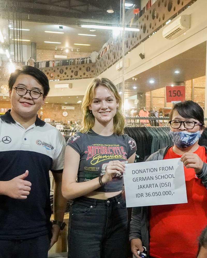 A group of people standing next to each other in a store holding a sign.