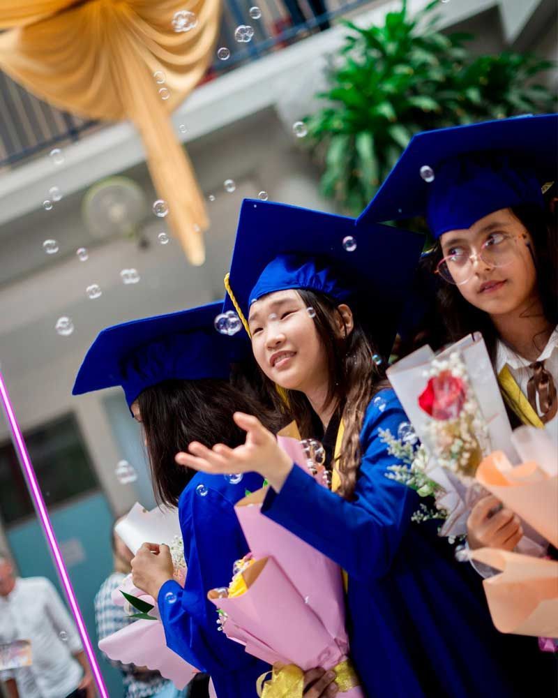 A group of girls in graduation caps and gowns holding bouquets of flowers