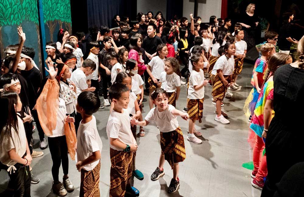 A large group of children are dancing on a stage.
