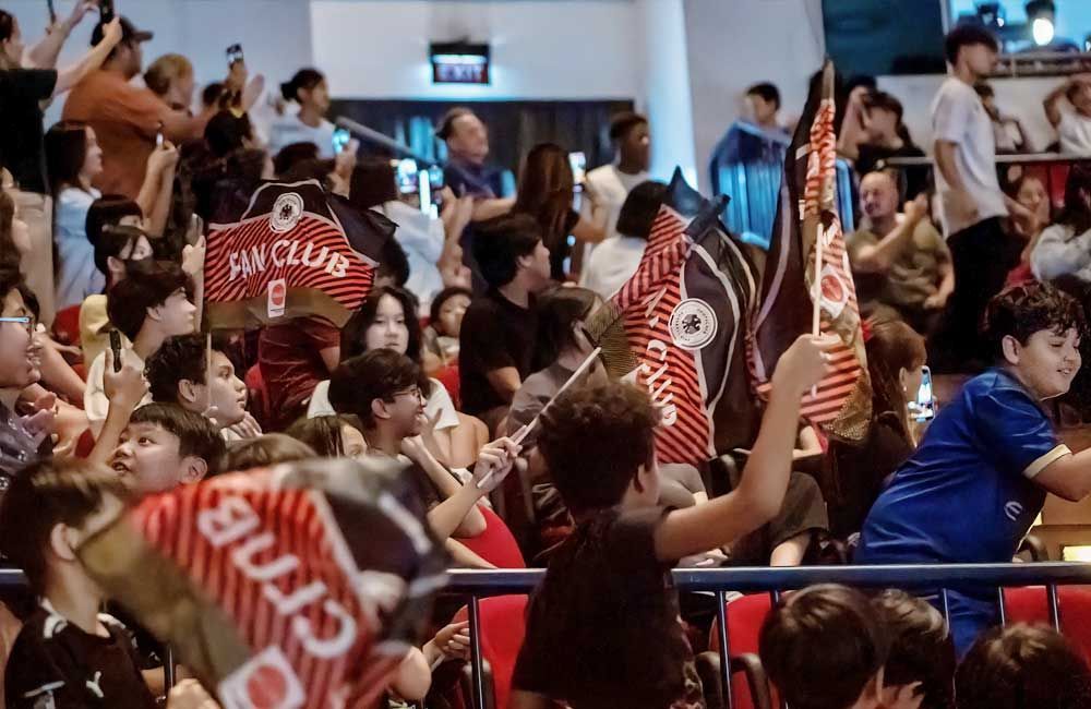 A crowd of people are sitting in a stadium holding flags.