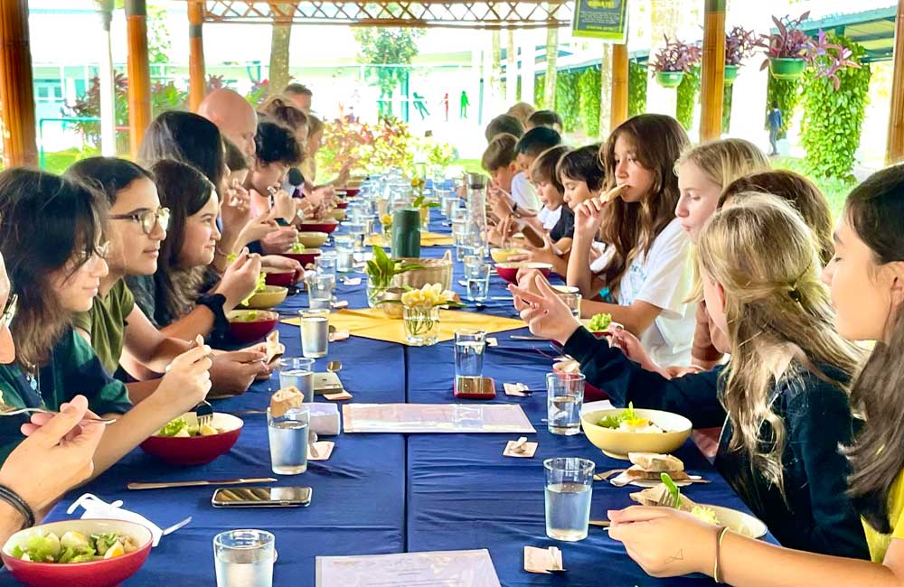 A group of people are sitting at a long table eating food.