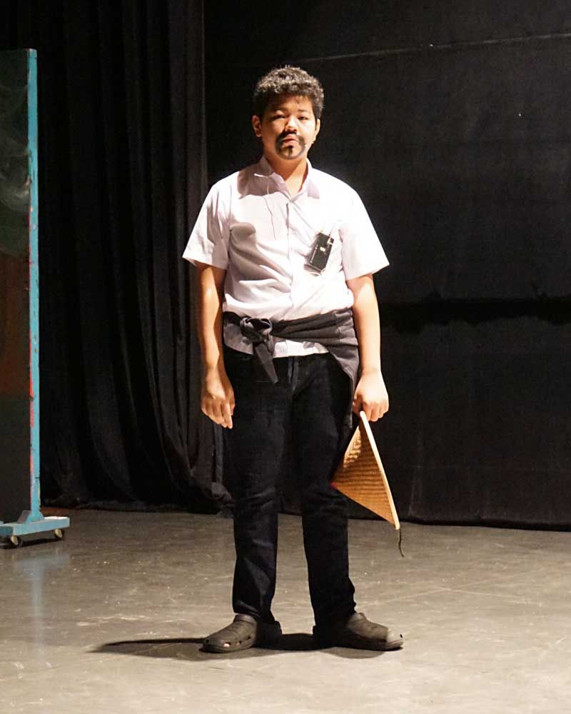 A young boy is standing on a stage holding a piece of wood