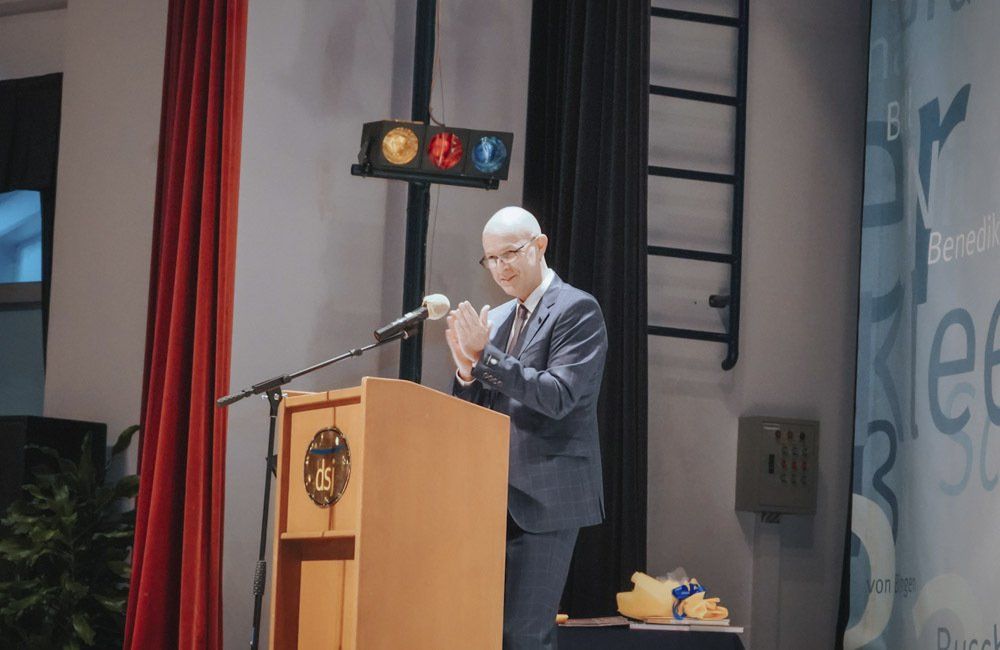 A man in a suit and tie is standing at a podium giving a speech.