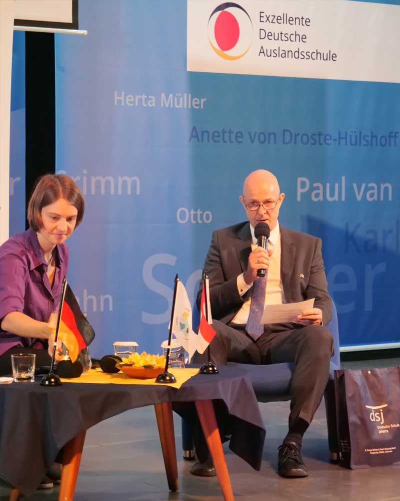 A man sitting at a table speaking into a microphone