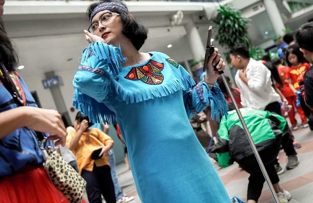 A woman in a blue dress is standing in a crowd of people.