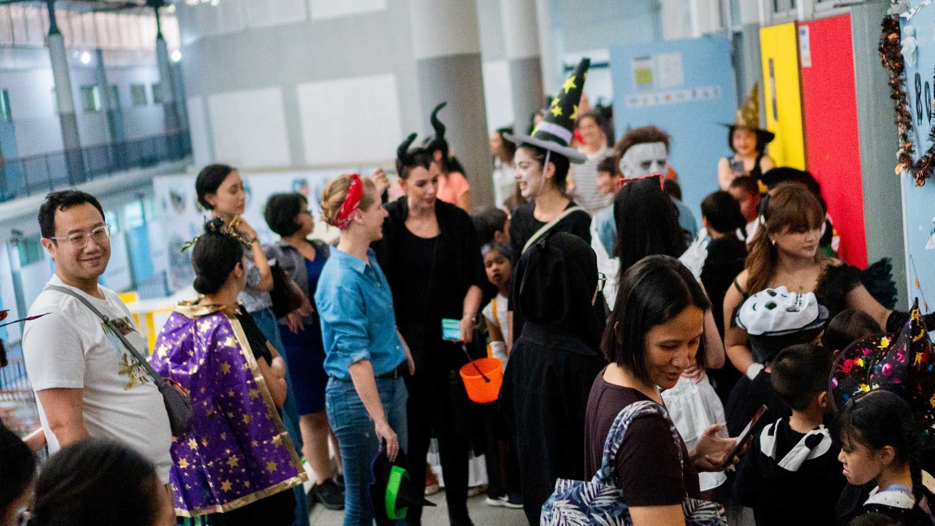A group of people dressed in halloween costumes are standing in a hallway.