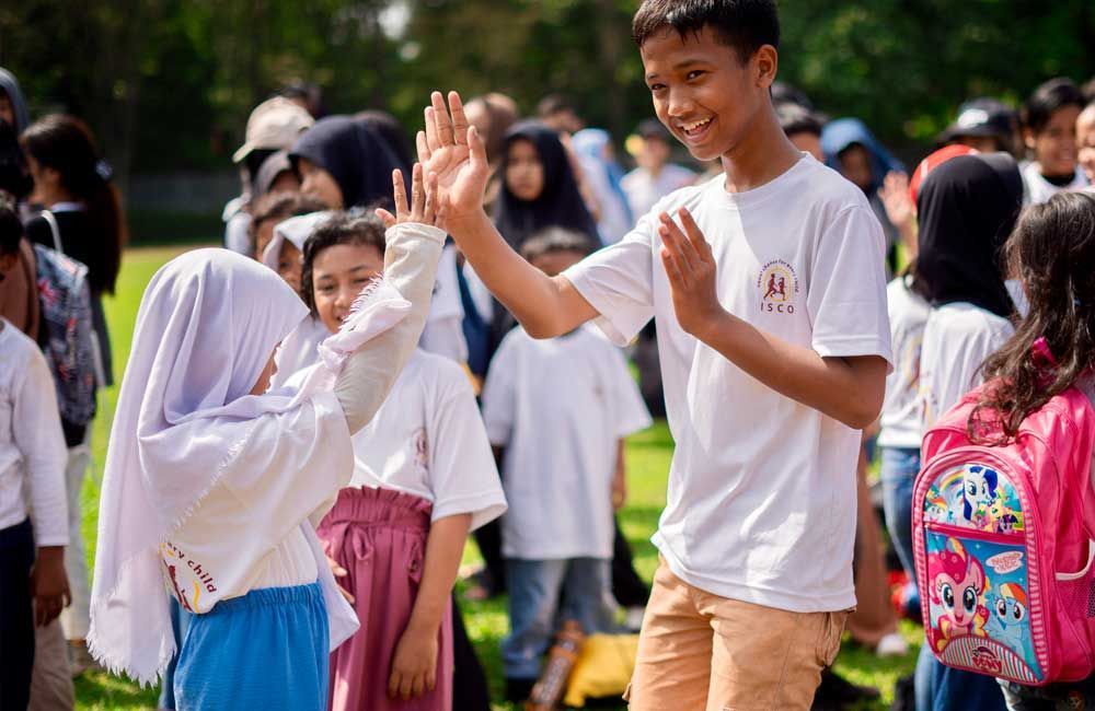 A boy and a girl are giving each other a high five.