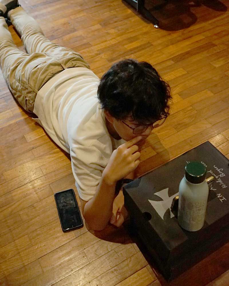A man is laying on the floor next to a box and a bottle
