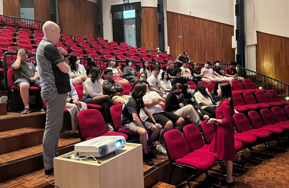 A group of people are sitting in an auditorium watching a presentation.