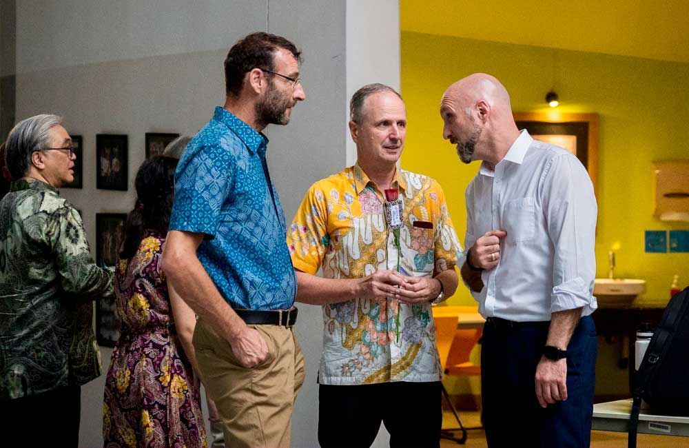 A group of men are standing in a room talking to each other.