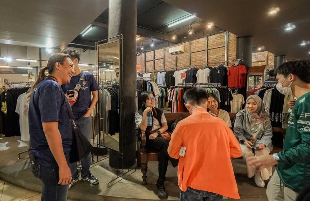 A group of people are standing in a store talking to each other.