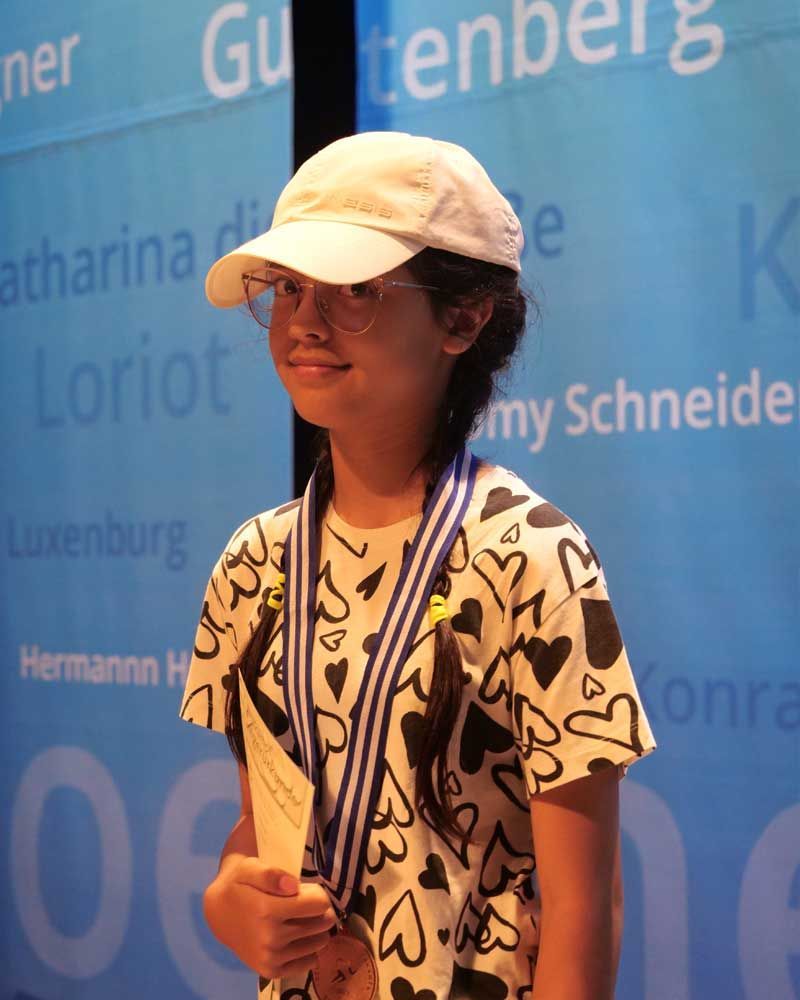 A young girl wearing a white hat and a medal