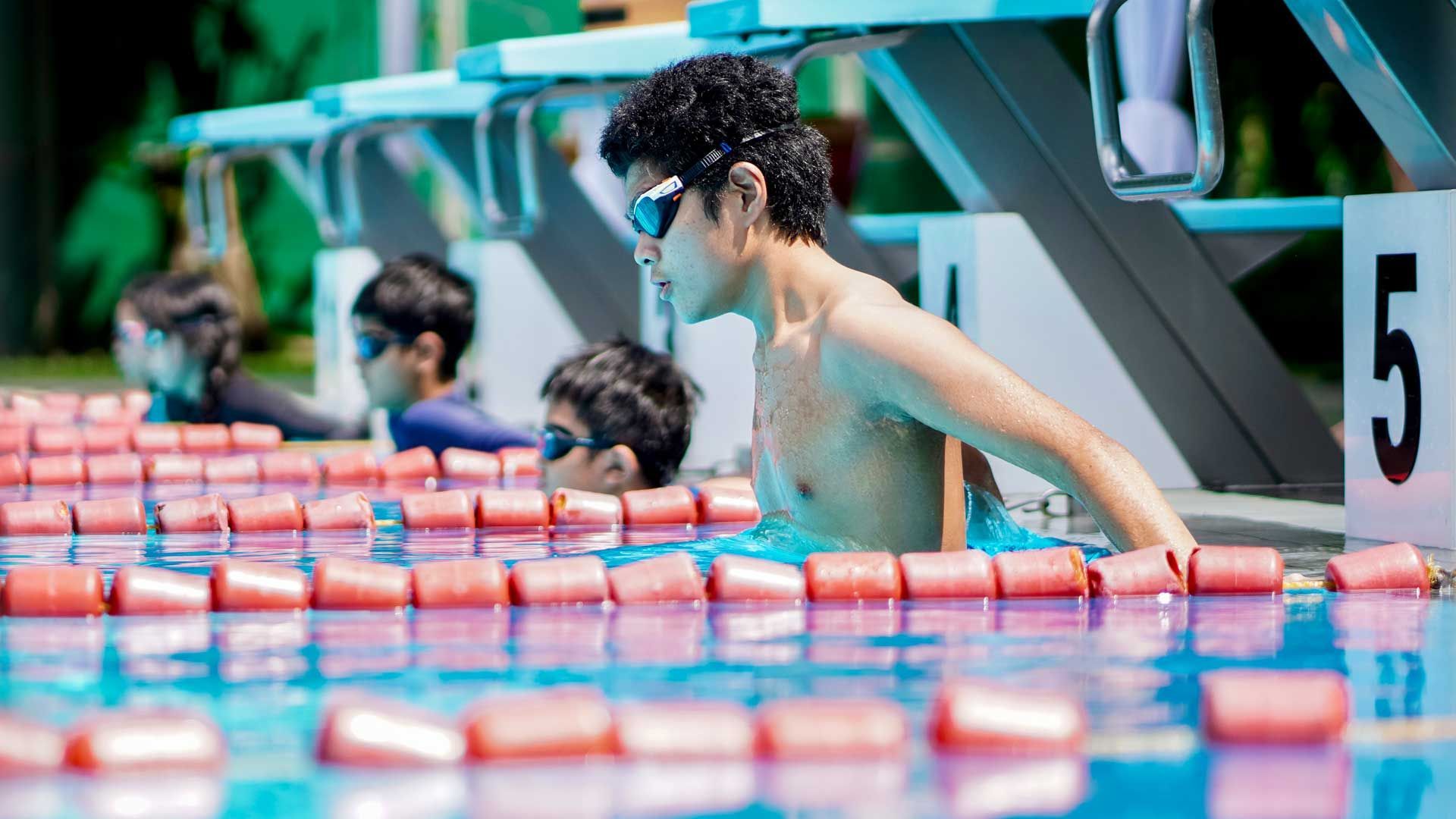A group of young men are swimming in a swimming pool.