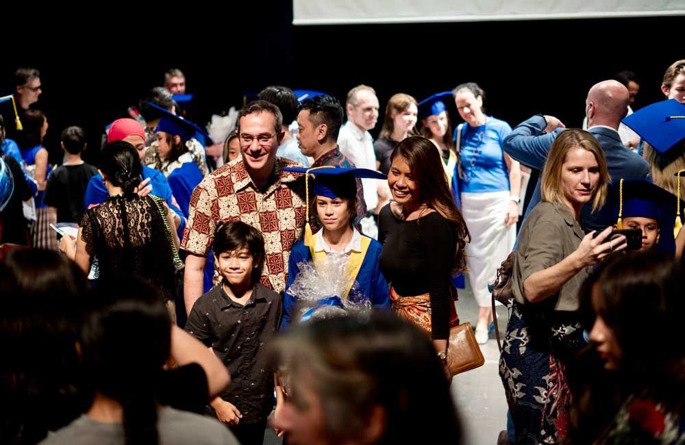 A group of people are standing in a crowd at a graduation ceremony.