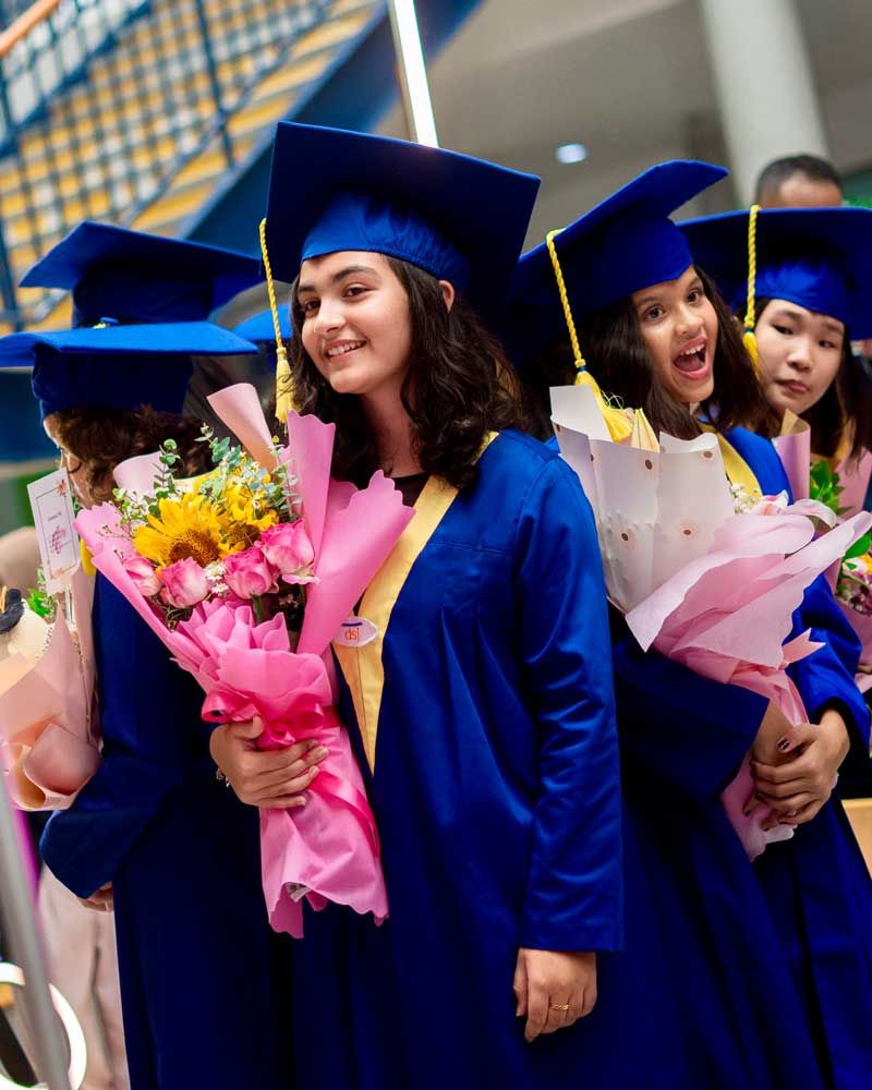A group of graduates are holding bouquets of flowers.