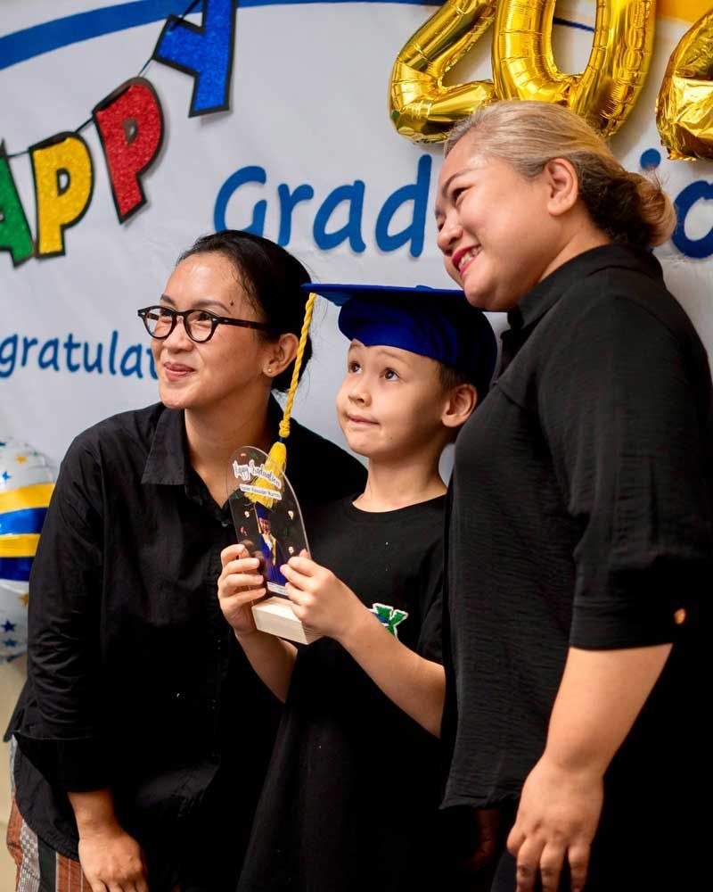 Two women and a child are posing for a picture at a graduation ceremony.