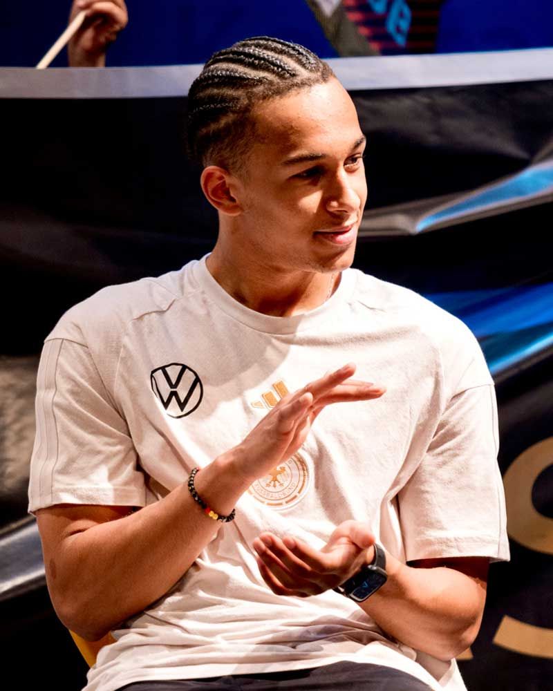 A young man wearing a white shirt with a vw logo on it