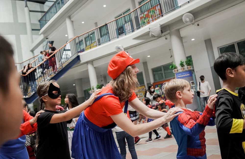 A group of children dressed in costumes are dancing in a hallway.