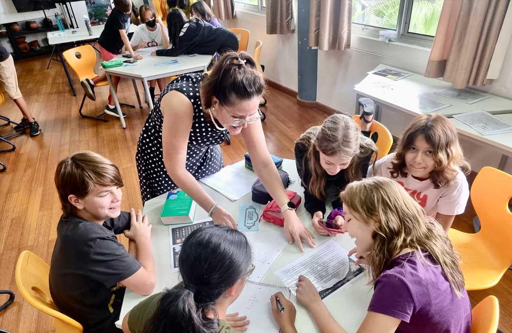 A group of children are sitting around a table with a teacher.