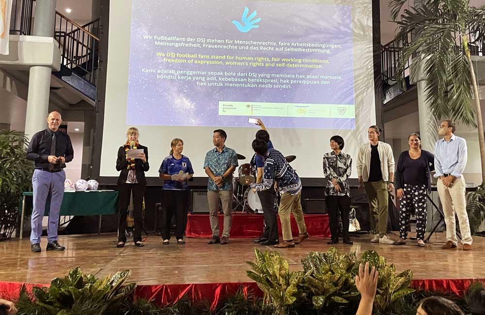 A group of people are standing on a stage in front of a large screen.
