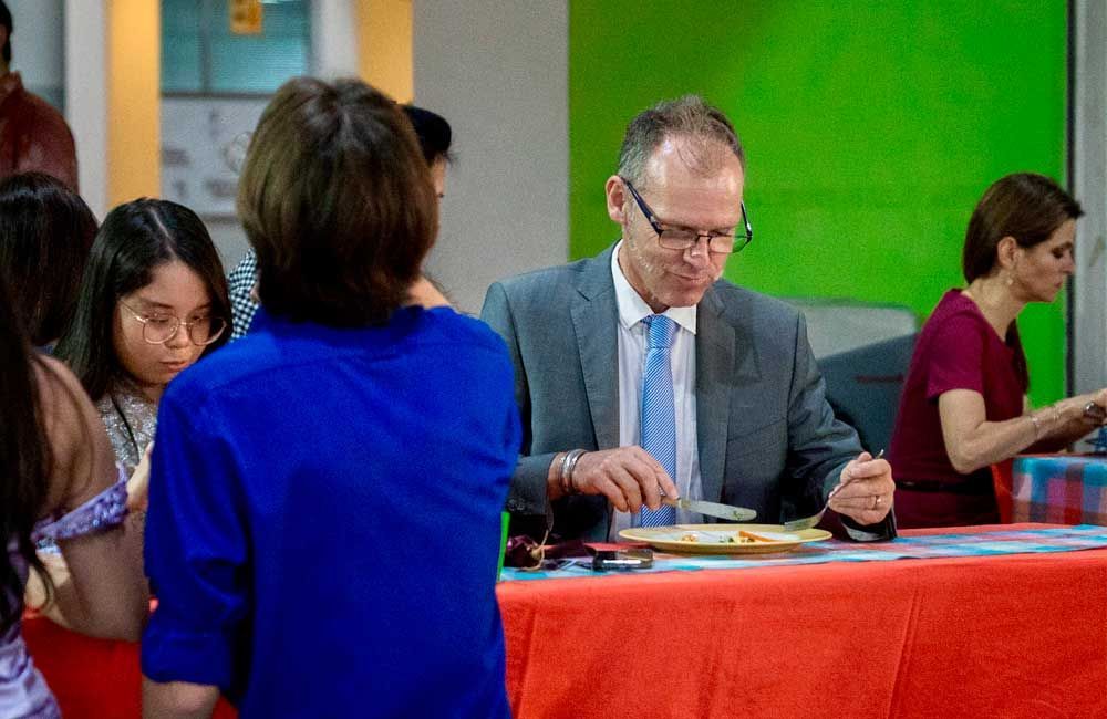 A man in a suit and tie is sitting at a table with a plate of food.