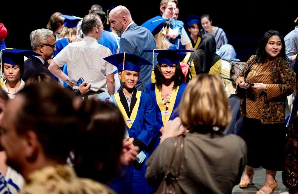 A group of people wearing graduation caps and gowns are standing in a crowd.