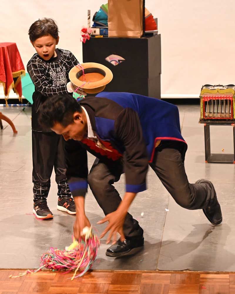 A man is kneeling down on the floor while a boy watches.