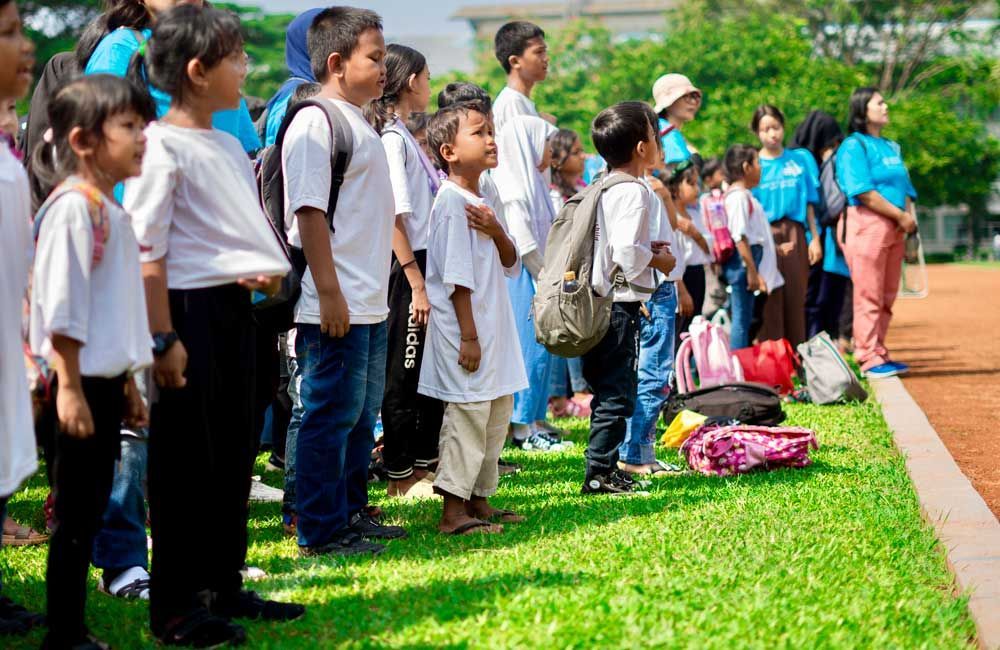 A group of children are standing on top of a lush green field.