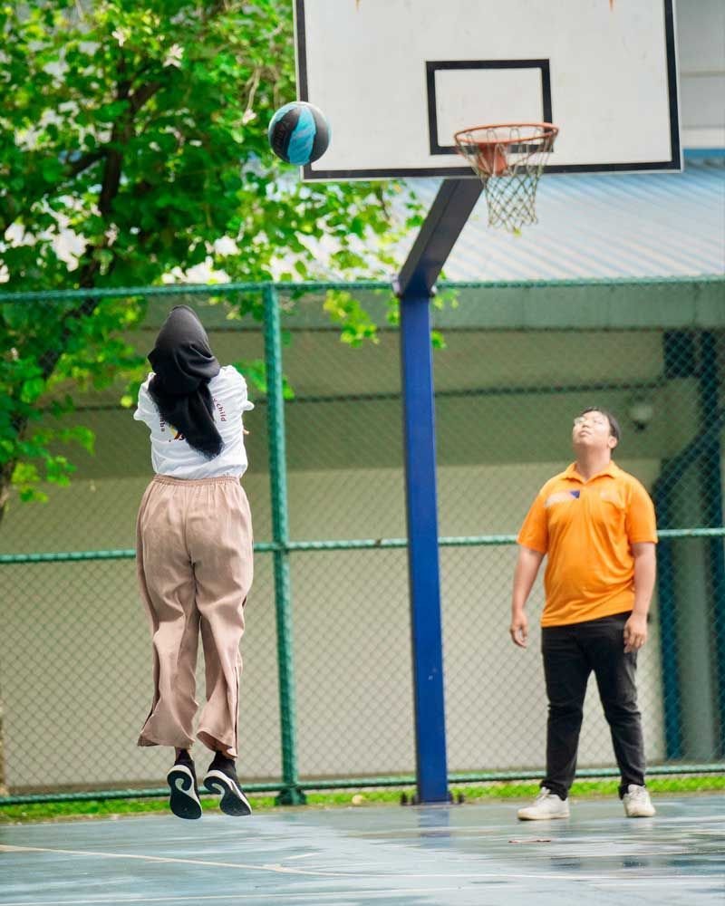 A man and a woman are playing basketball on a court.