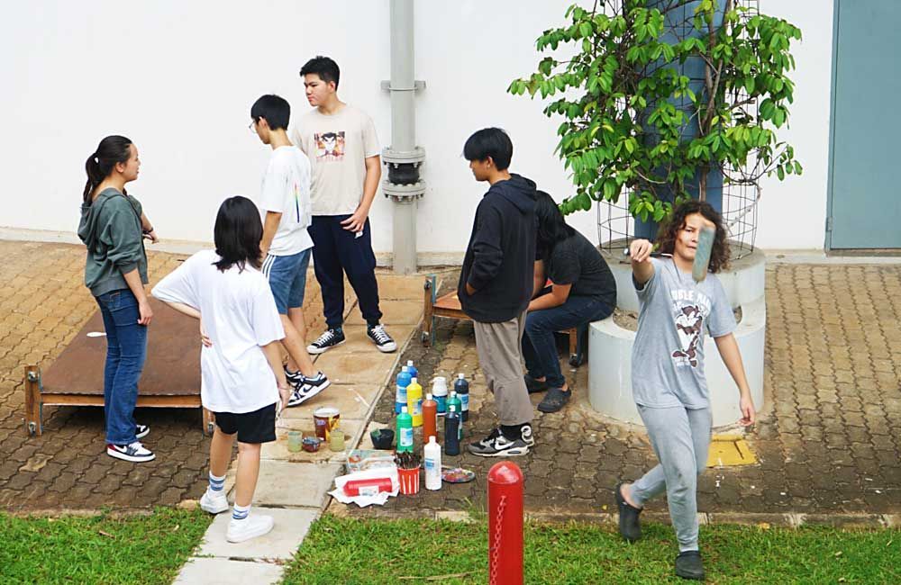 A group of people are standing on a sidewalk in front of a building.