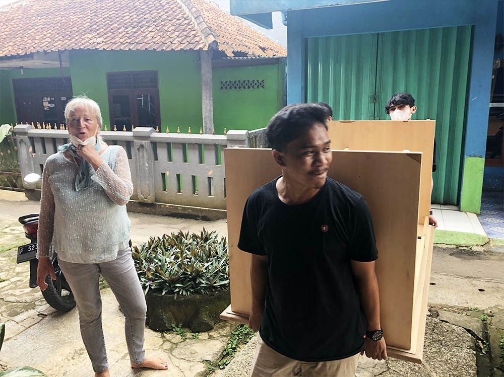 A man is carrying a large piece of wood next to a woman.