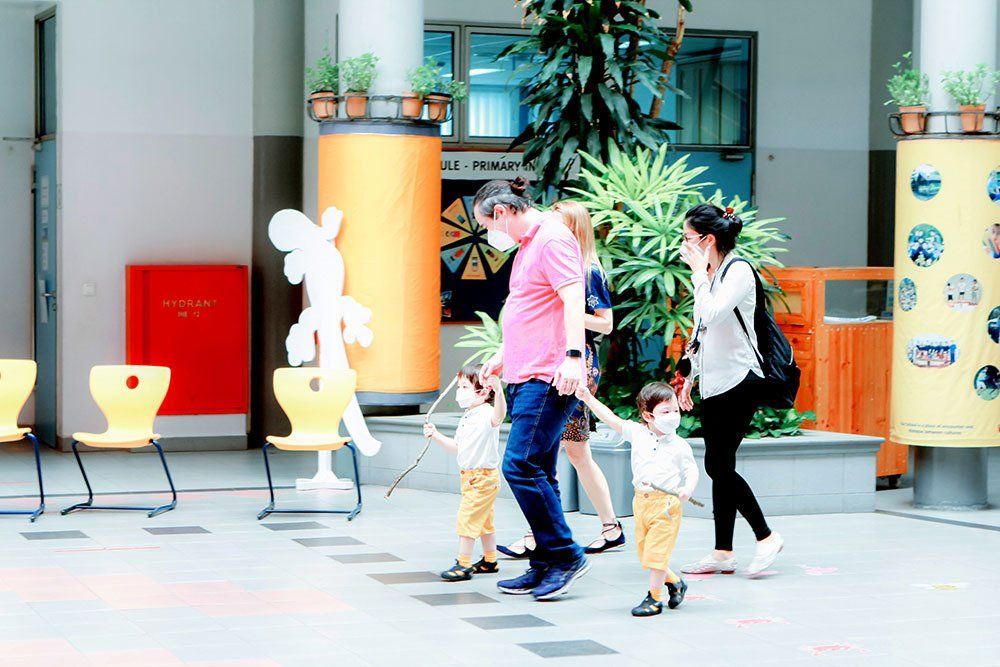 A family is walking down a sidewalk holding hands.