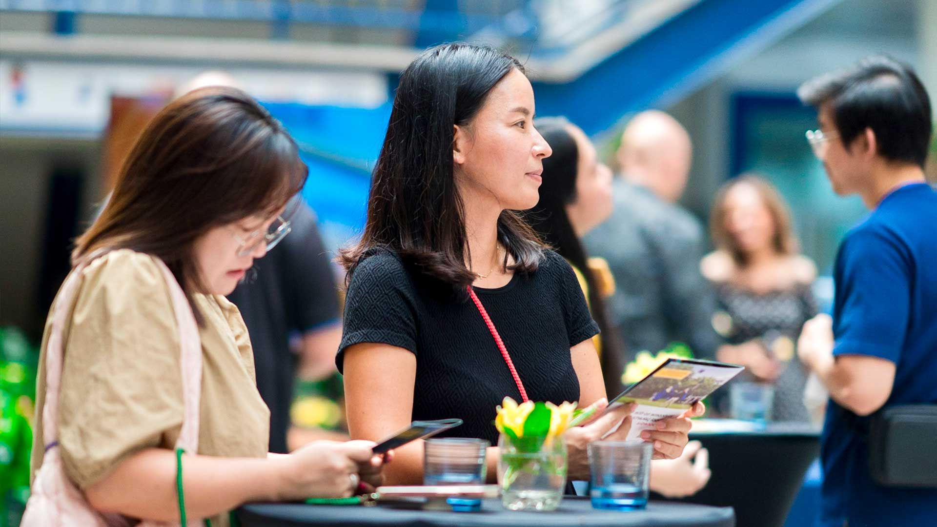 Two women are sitting at a table looking at their phones.