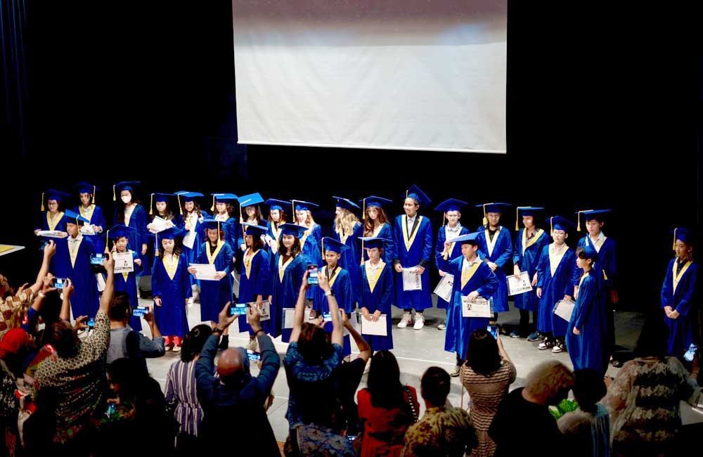 A group of graduates are standing on a stage in front of a crowd.
