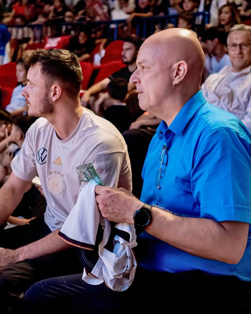 A man in a blue shirt is sitting next to another man in a white shirt.