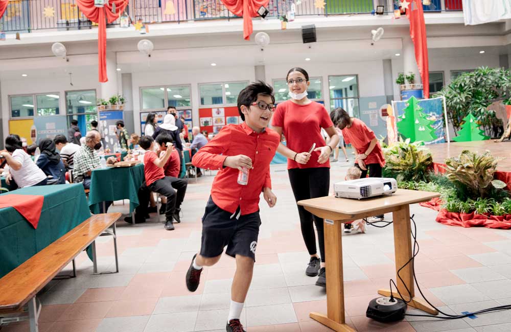 A boy is running towards a table with a projector on it.