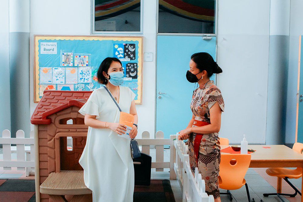 Two women wearing masks are standing next to each other in a room.