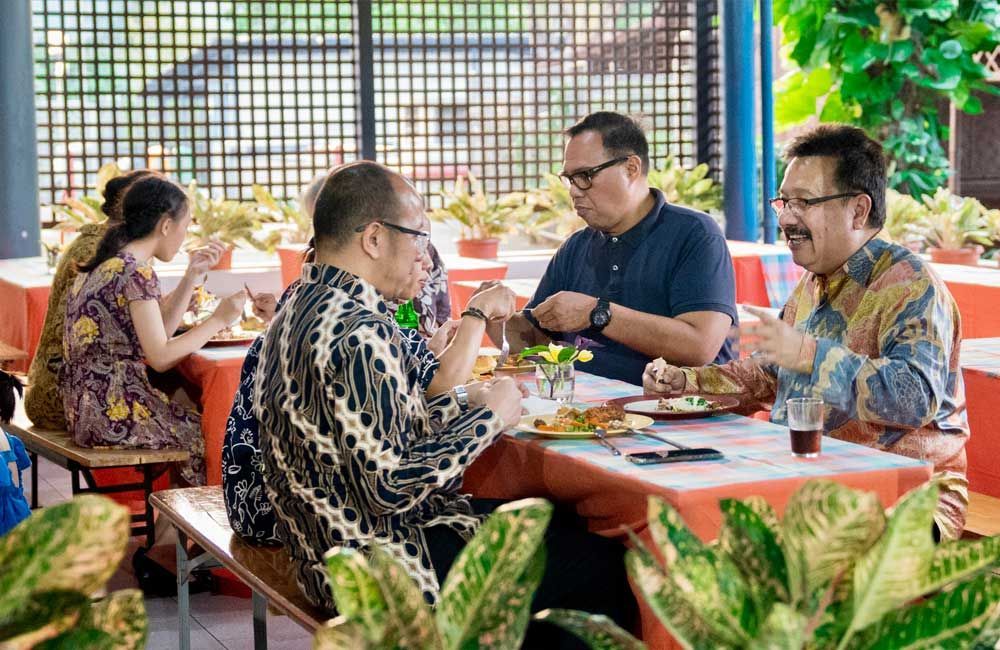 A group of people are sitting at tables eating food.