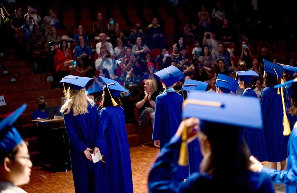 A group of graduates are standing on a stage in front of a crowd.