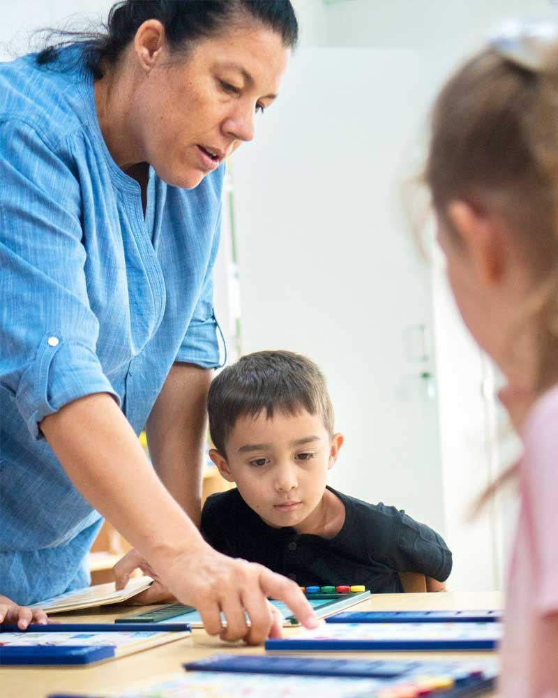 A woman is teaching a group of children in a classroom.