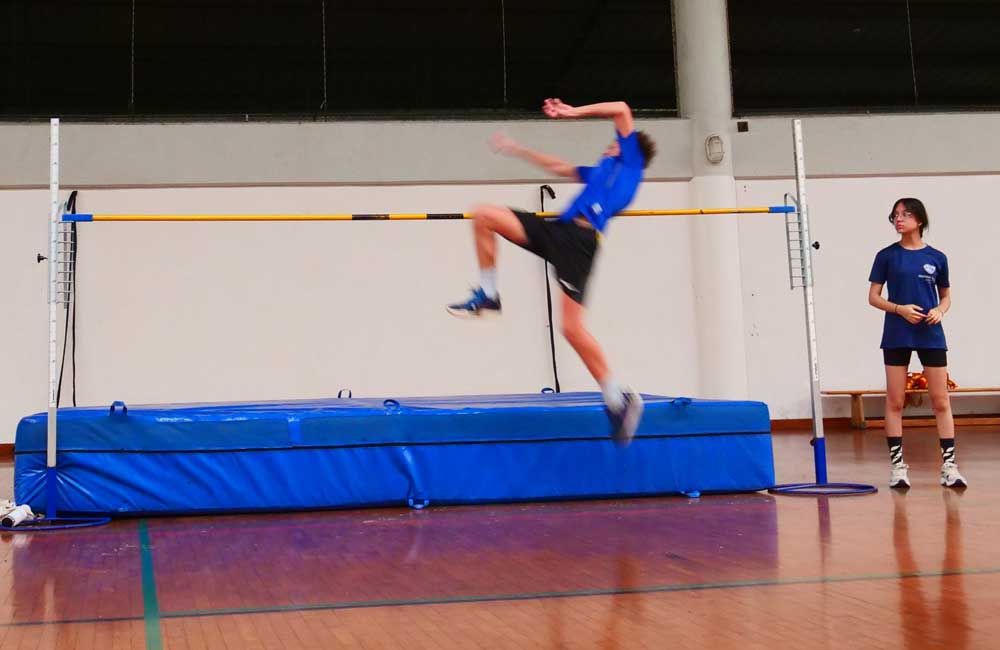 A man is jumping over a bar in a gym