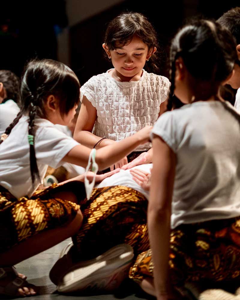 A group of young girls are sitting on the floor playing with each other.