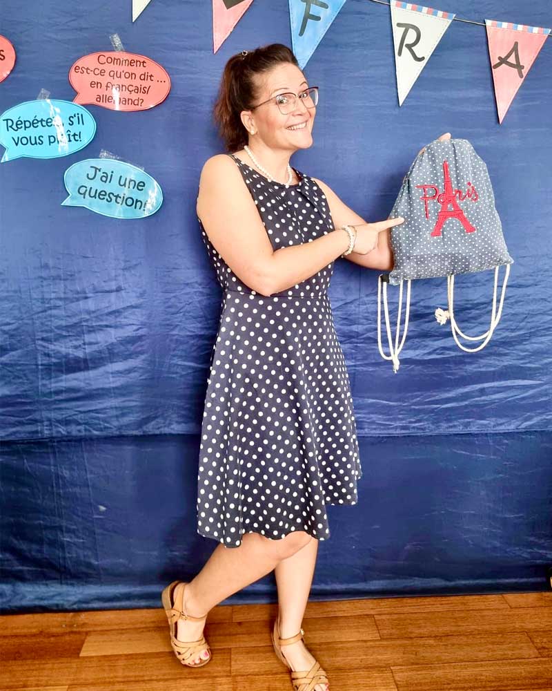 A woman in a polka dot dress is holding a drawstring bag