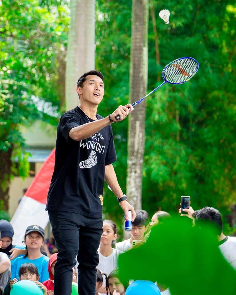 A man is holding a badminton racket in front of a crowd of people.
