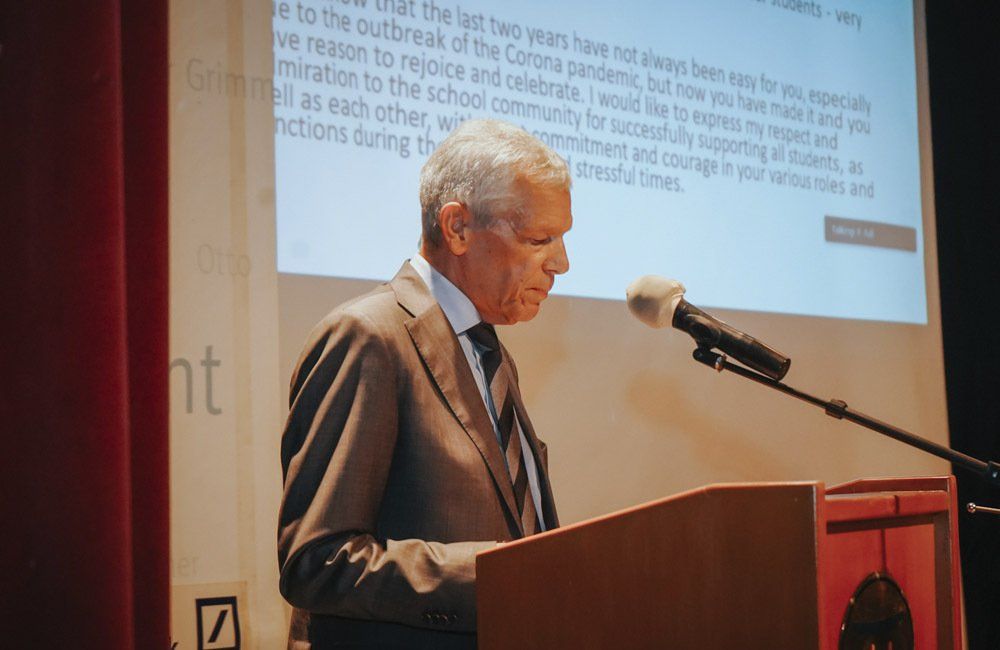 A man in a suit and tie is standing at a podium speaking into a microphone.