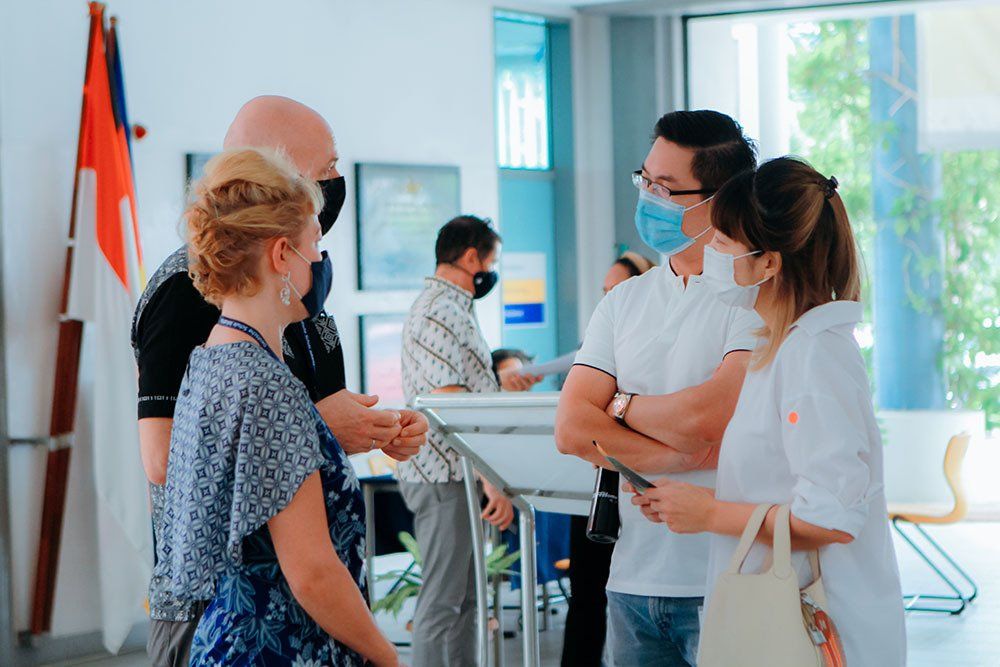 A group of people wearing face masks are standing next to each other in a room.