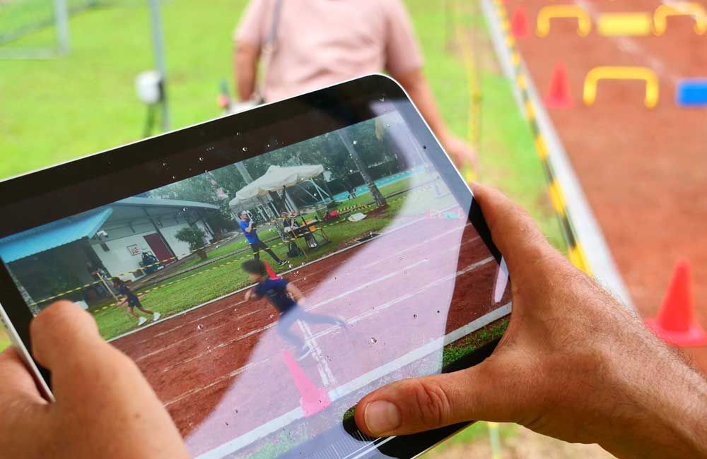 A person is holding a tablet with a picture of a race on it.
