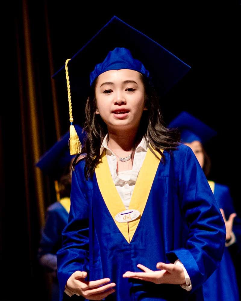 A young girl wearing a graduation cap and gown