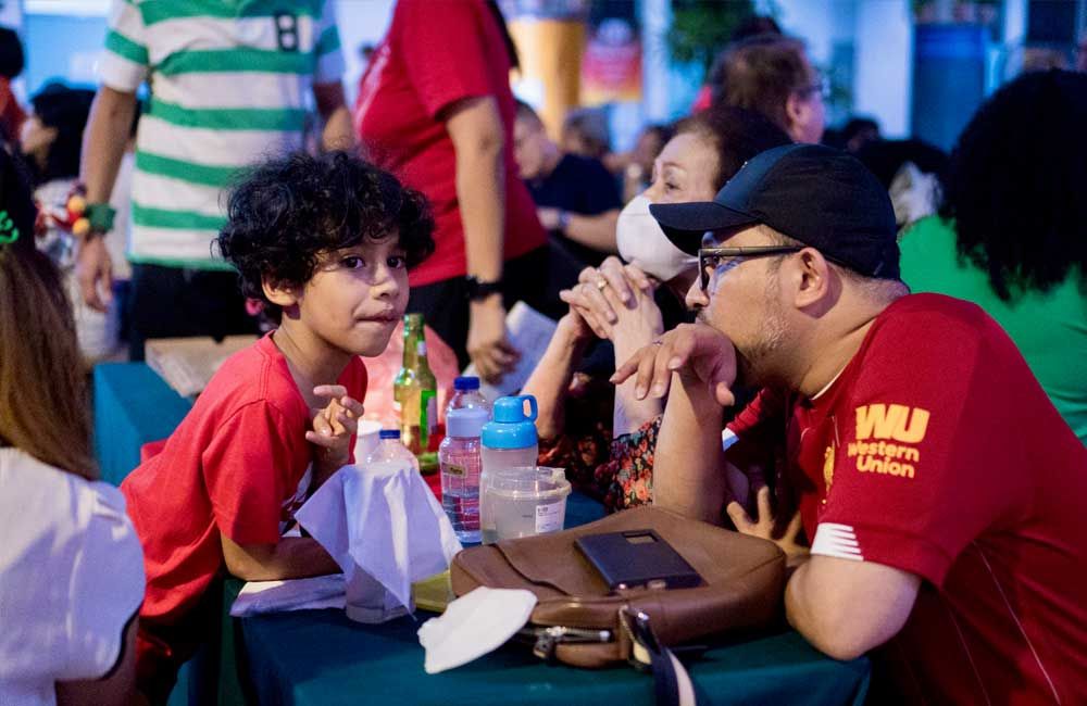 A man and a boy are sitting at a table talking to each other.