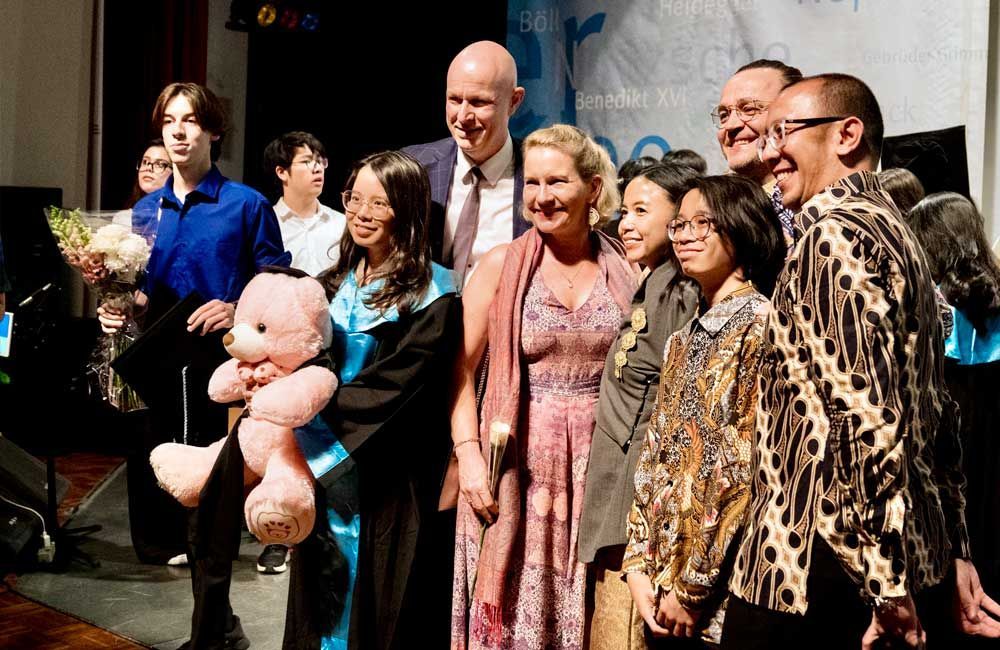 A group of people posing for a picture with a girl holding a teddy bear.
